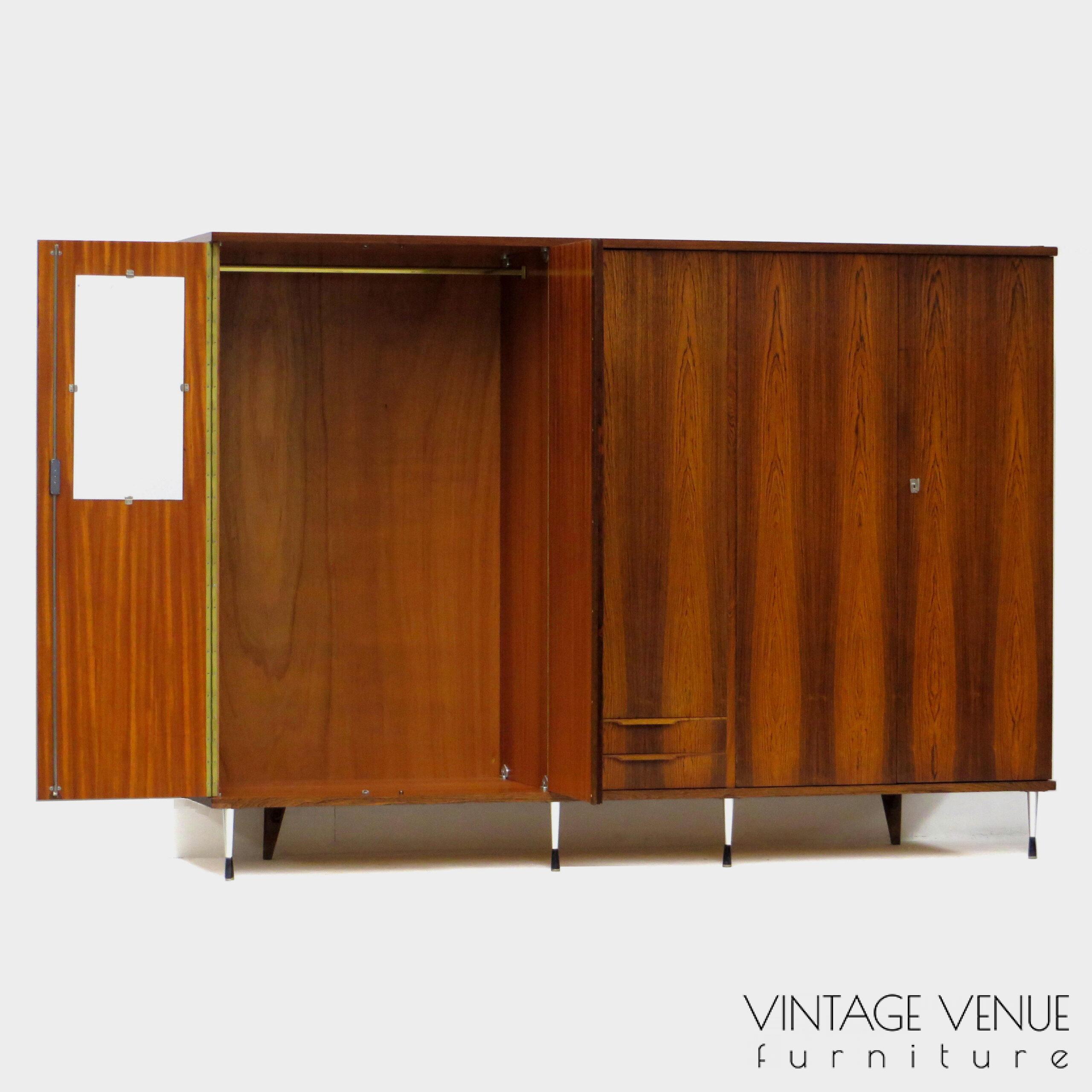 EN: 5-door vintage designer wardrobe in high quality rosewood rosewood, with stylish adjustable legs, 2 drawers with pretty handles, 4 shelves, 2 brass hanging rails, a mirror, and very sturdy adjustable & stylish metal legs. Period: 1960s. Condition: fully functional working and generally in good condition. Slight signs of use commensurate with age. ENG: Rare and exclusive high quality vintage mid century modern design wardrobe made of rosewood / rosewood. It has 5 doors, 2 drawers with beautiful carved handles, 4 shelves, 2 brass hang supports, a mirror and adjustable stylish and very solid metal legs. Period: 1960s. Condition: fully functional and overall in good condition. Light wear consistent with age and use. EN: 5-door vintage designer wardrobe in high quality rosewood rosewood, with stylish adjustable legs, 2 drawers with pretty handles, 4 shelves, 2 brass hanging rails, a mirror, and very sturdy adjustable & stylish metal legs. Period: 1960s. Condition: fully functional working and generally in good condition. Slight signs of use commensurate with age. ENG: Rare and exclusive high quality vintage mid century modern design wardrobe made of rosewood / rosewood. It has 5 doors, 2 drawers with beautiful carved handles, 4 shelves, 2 brass hang supports, a mirror and adjustable stylish and very solid metal legs. Period: 1960s. Condition: fully functional and overall in good condition. Light wear consistent with age and use.