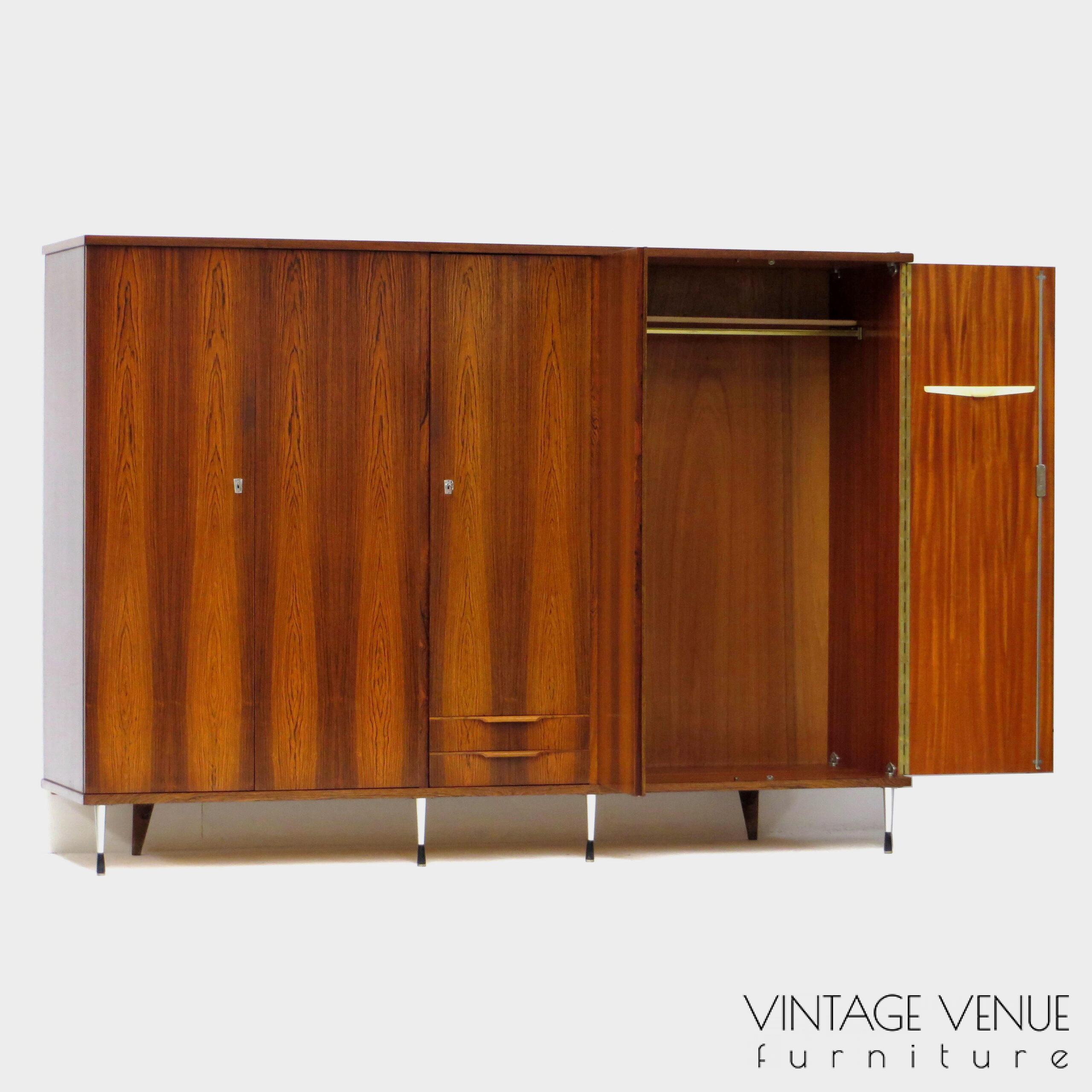 EN: 5-door vintage designer wardrobe in high quality rosewood rosewood, with stylish adjustable legs, 2 drawers with pretty handles, 4 shelves, 2 brass hanging rails, a mirror, and very sturdy adjustable & stylish metal legs. Period: 1960s. Condition: fully functional working and generally in good condition. Slight signs of use commensurate with age. ENG: Rare and exclusive high quality vintage mid century modern design wardrobe made of rosewood / rosewood. It has 5 doors, 2 drawers with beautiful carved handles, 4 shelves, 2 brass hang supports, a mirror and adjustable stylish and very solid metal legs. Period: 1960s. Condition: fully functional and overall in good condition. Light wear consistent with age and use. EN: 5-door vintage designer wardrobe in high quality rosewood rosewood, with stylish adjustable legs, 2 drawers with pretty handles, 4 shelves, 2 brass hanging rails, a mirror, and very sturdy adjustable & stylish metal legs. Period: 1960s. Condition: fully functional working and generally in good condition. Slight signs of use commensurate with age. ENG: Rare and exclusive high quality vintage mid century modern design wardrobe made of rosewood / rosewood. It has 5 doors, 2 drawers with beautiful carved handles, 4 shelves, 2 brass hang supports, a mirror and adjustable stylish and very solid metal legs. Period: 1960s. Condition: fully functional and overall in good condition. Light wear consistent with age and use.